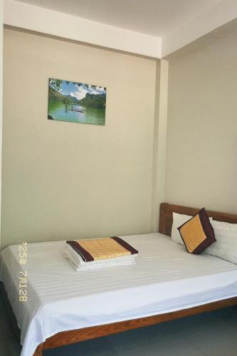 a bed in a room with a picture on the wall at Ba Be Lake - Nhà Nghỉ Thư Nhạc in Bak Kan