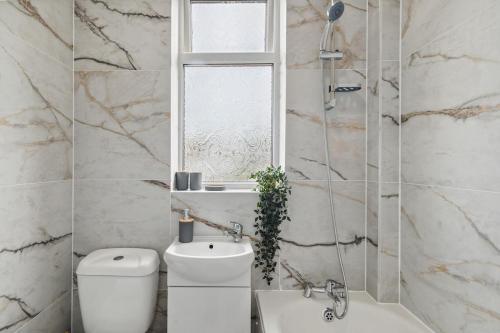 a bathroom with a toilet and a sink and a window at Large 5Bed House London Next CUH Free Parking in Mitcham Junction