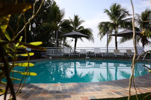 a swimming pool with chairs and umbrellas at Eco Torarica in Paramaribo