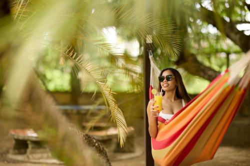 a woman sitting in a hammock holding a banana at Eco Torarica in Paramaribo