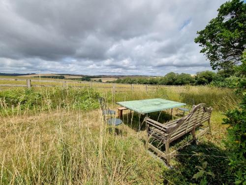 a picnic table with a bench in a field at Country Home in Idyllic South Downs - Views, Free Parking for 7 cars, Play room, Steam room, Fire Pit and more in Kingston near Lewes