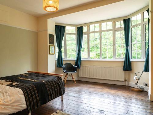 a bedroom with a bed and a chair and windows at Country Home in Idyllic South Downs - Views, Free Parking for 7 cars, Play room, Steam room, Fire Pit and more in Kingston near Lewes