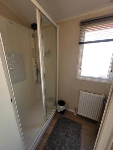 a walk in shower in a bathroom with a window at The mistral lido beach Prestatyn in Prestatyn