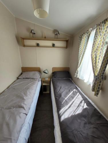 a small bedroom with two beds in a trailer at The mistral lido beach Prestatyn in Prestatyn