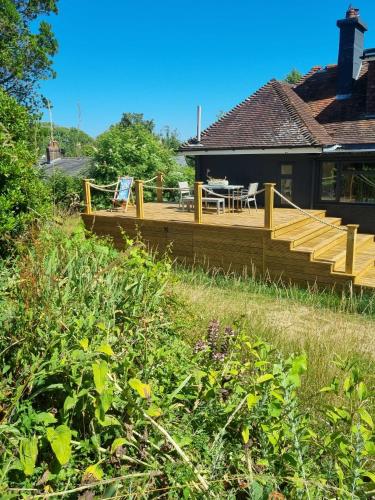 a deck with a table and chairs on a house at Country Home in Idyllic South Downs - Views, Free Parking for 7 cars, Play room, Steam room, Fire Pit and more in Kingston near Lewes