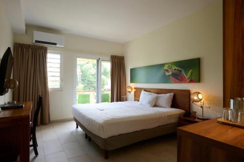 a hotel room with a bed and a window at Eco Torarica in Paramaribo