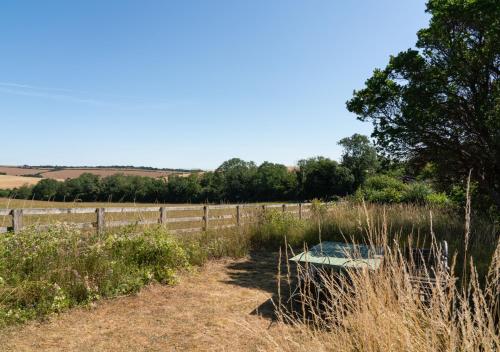 a bench sitting in a field next to a fence at Country Home in Idyllic South Downs - Views, Free Parking for 7 cars, Play room, Steam room, Fire Pit and more in Kingston near Lewes