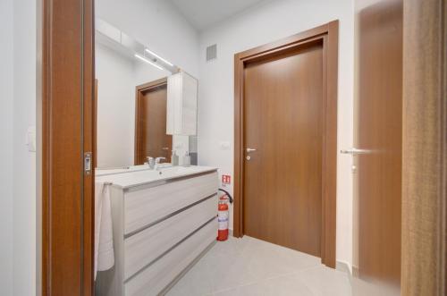 a bathroom with a sink and a wooden door at SGHouse appartamento con parcheggio gratuito in Rivoli