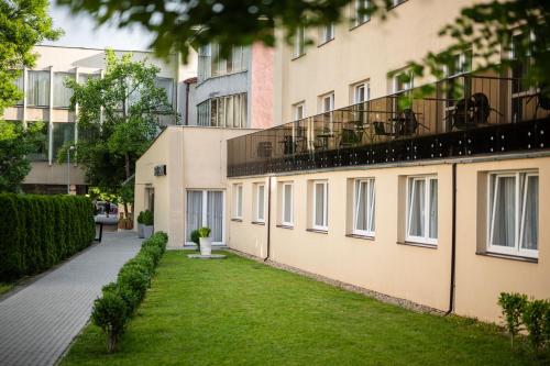 an apartment building with a green lawn in front of it at Hotel Metropol CB in České Budějovice