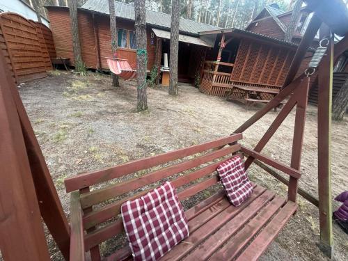 a wooden bench with two pillows on it in a yard at POD SOSNAMI Ośrodek Wypoczynkowy Boszkowo Letnisko in Boszkowo