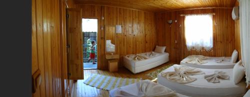 a room with two beds in a wooden room with a window at Korsan Pension in Olympos