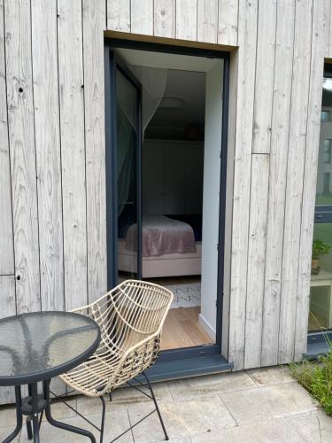 a glass table and a chair next to a building at Piejūras apartaments in Ķesterciems