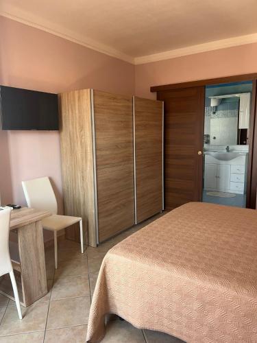a bedroom with a bed and a table and cabinets at Casa vacanze Sandalia in Bosa