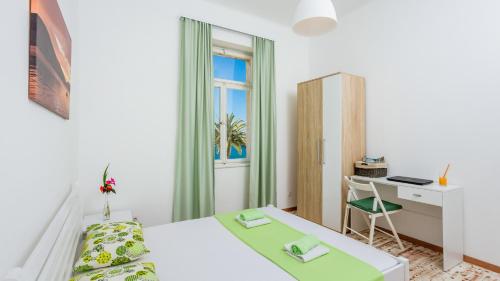 a white bedroom with a bed and a desk at Riva Guesthouse in Tivat