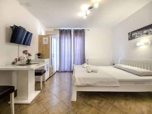 a white bedroom with a bed and a kitchen at Guest House Mačić in Korenica