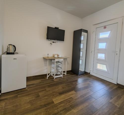 a room with a refrigerator and a table and a television at Guest House Mačić in Korenica