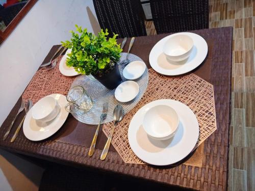 a table with white plates and a vase with a plant at Cozy Home in Dadiangas, General Santos City - Perfect for Families 