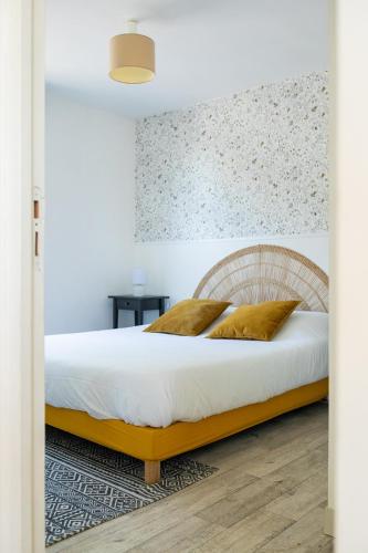 a bedroom with a bed with white sheets and gold pillows at La Casinière Coëtquidan in Guer