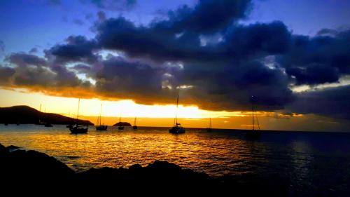 a group of boats in the water at sunset at Chambre Caribéenne in Les Trois-Îlets