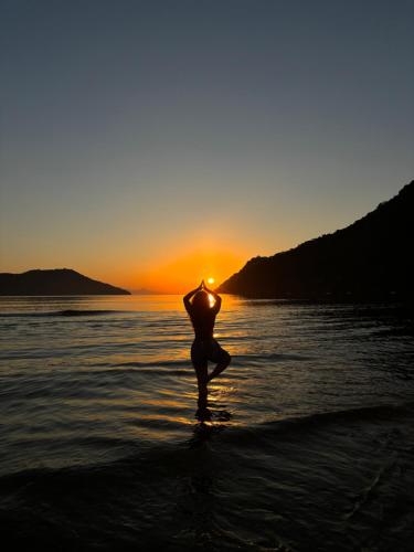 a person standing in the water at the beach at sunset at Casa natureza in Paraty