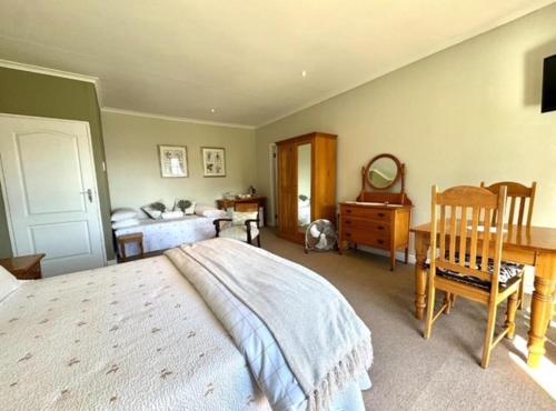 a bedroom with a bed and a desk and a table at Amanzi Guesthouse in Gqeberha