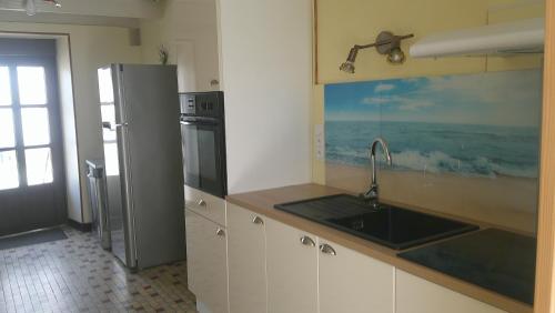 a kitchen with a sink and a refrigerator at Maison entre Cherbourg et Mont Saint Michel in Saint-Aubin-du-Perron