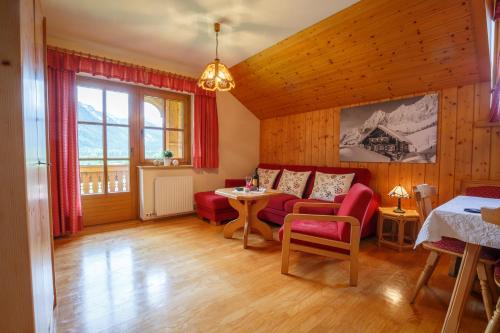 a living room with a red couch and a table at Landhaus Birgbichler - Apartments mit Bergblick inklusive Sommercard in Ramsau am Dachstein