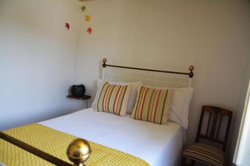 a bedroom with a bed with white sheets and pillows at Casa do Alfaiate in Chãos