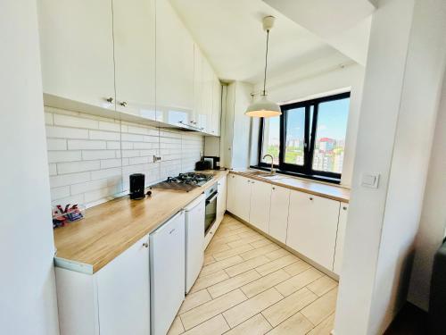 Una cocina con gabinetes blancos y una ventana grande. en Iulius Mall New Residence, en Iaşi