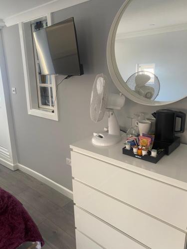 a bedroom with a dresser with a mirror and a dresser with a fan at OneDouble room, one small double room, one en-suite studio room near to Wembley stadium in London