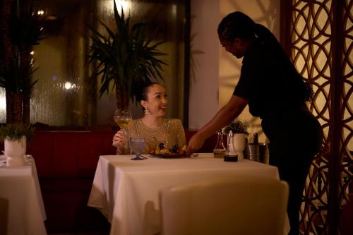a woman standing next to a table with a woman holding a glass at Royal Torarica in Paramaribo