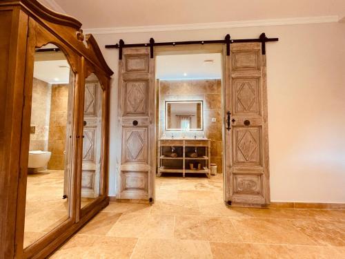 a bathroom with a large wooden door and a mirror at La Réserve Provence in Vaugines