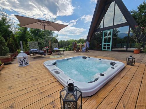 a hot tub on a wooden deck with an umbrella at Api Aframe in Avrig