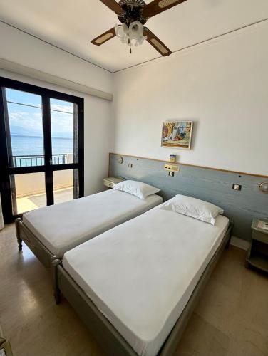 two beds in a bedroom with a view of the ocean at Hotel Derveni Georgiadis in Stómion
