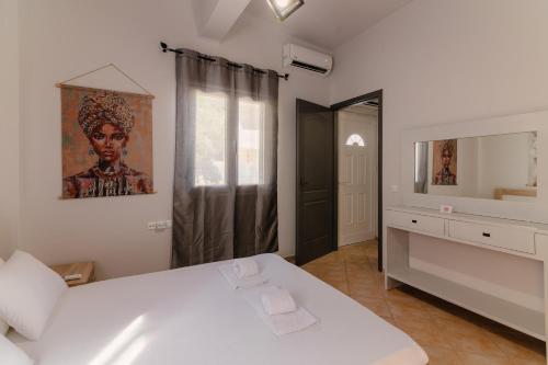 a bedroom with a white bed and a mirror at Coastal Bliss- Tsoutsouros in Tsoútsouros