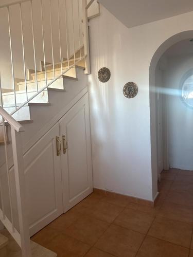 a hallway with a staircase with white walls at Villa con Piscina climatizada in Sanlúcar de Barrameda