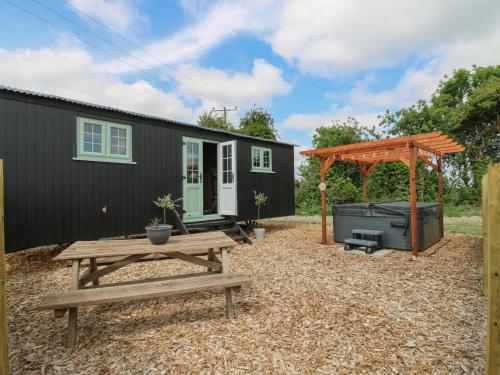 a backyard with a picnic table and a black house at Luxury Shepherd Hut with Private Hot Tub in Swaffham Bulbeck