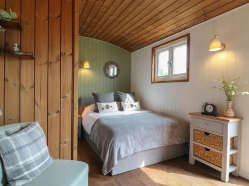 a bedroom with a bed and a chair at Luxury Shepherd Hut with Private Hot Tub in Swaffham Bulbeck