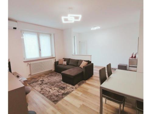 una sala de estar con un sofá y una mesa en Appartamento Julia Trilocale Open Space - Tolmezzo UD, en Tolmezzo