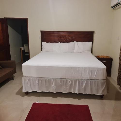 a bedroom with a large white bed with a wooden headboard at Paradise Place Grande King in Cave Hill