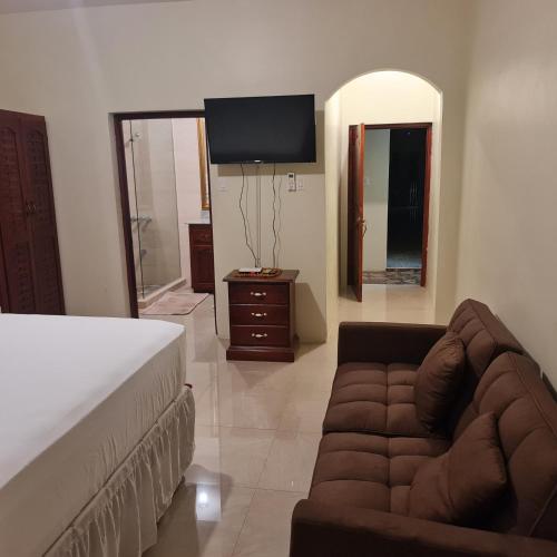 a bedroom with a bed and a couch and a tv at Paradise Place Grande King in Cave Hill