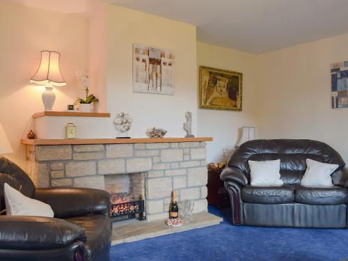 a living room with two leather chairs and a fireplace at Craigrossie Cottage in Auchterarder