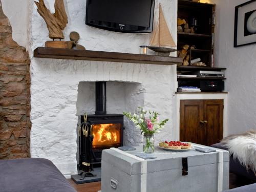 a living room with a fireplace and a table with flowers at Fishlegs in Brixham