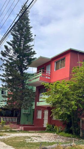 a red house with a tree in front of it at Estrella de Mar in Pedernales