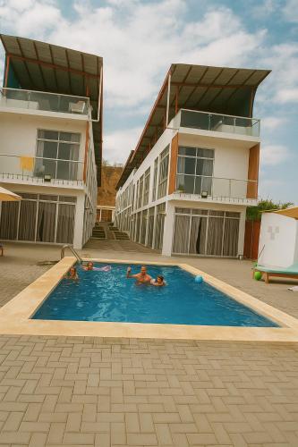 two people in a swimming pool next to a building at Plateia - Casa de Playa en Zorritos in Bocapán