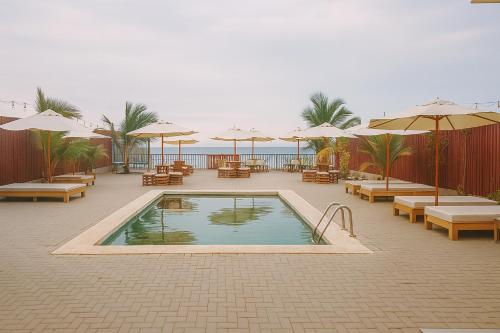a swimming pool with tables and chairs and umbrellas at Plateia - Casa de Playa en Zorritos in Bocapán