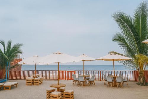 a patio with tables and chairs and umbrellas on the beach at Plateia - Casa de Playa en Zorritos in Bocapán