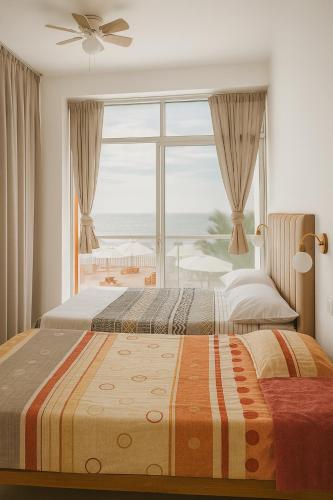 two beds in a bedroom with a large window at Plateia - Casa de Playa en Zorritos in Bocapán