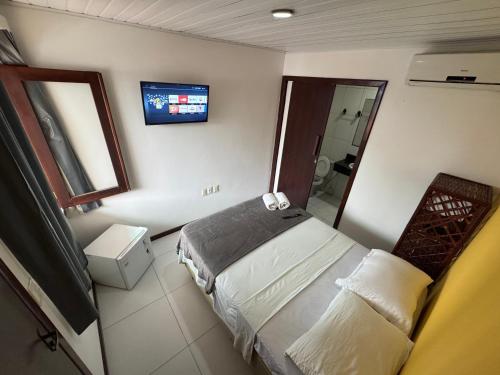 a bedroom with a bed and a tv on the wall at Pousada Piratas Do Morro Segunda Praia in Morro de São Paulo