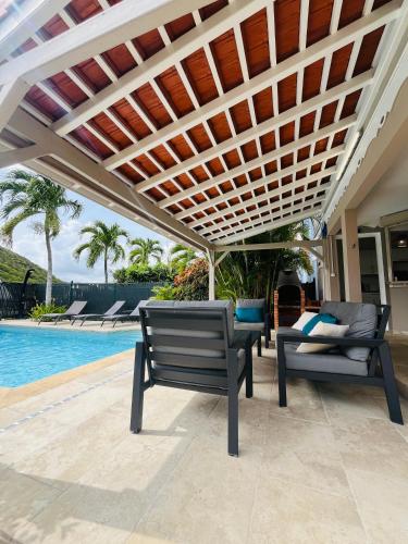 Un patio con dos bancos bajo toldo junto a una piscina. en Villa dO, en Sainte-Anne